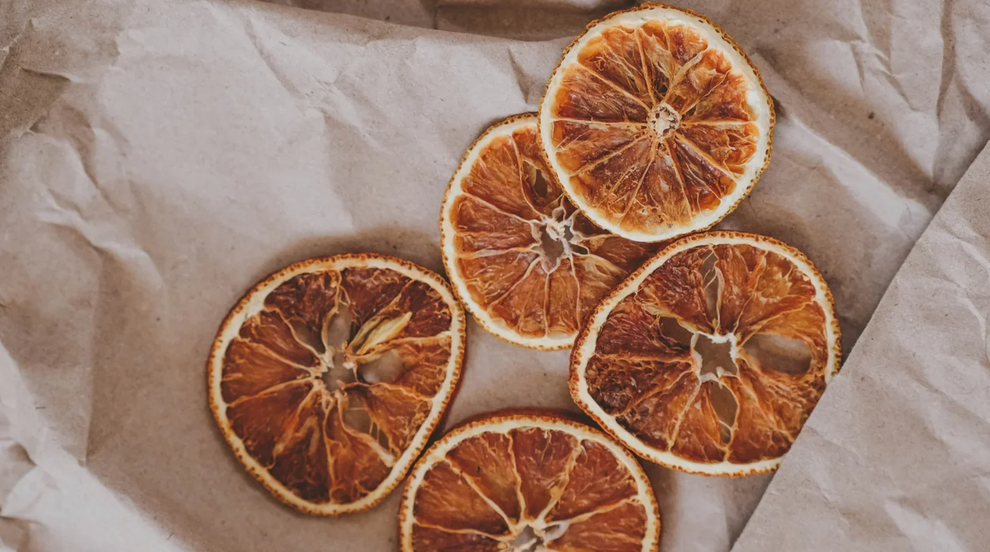 Five dried orange slices on brown parchment paper, arranged in a cluster.